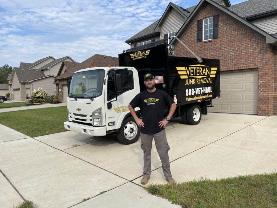 A Veteran Junk Removal crew member standing in a driveway in front of the branded truck