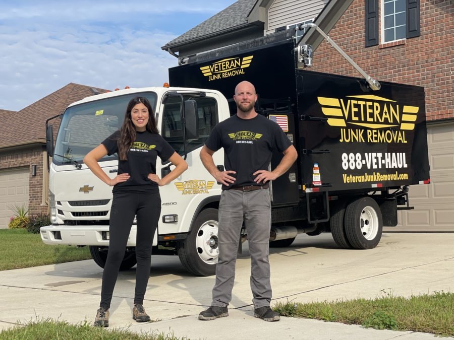 Two Veteran Junk Removal team members standing in a driveway in front of the branded truck