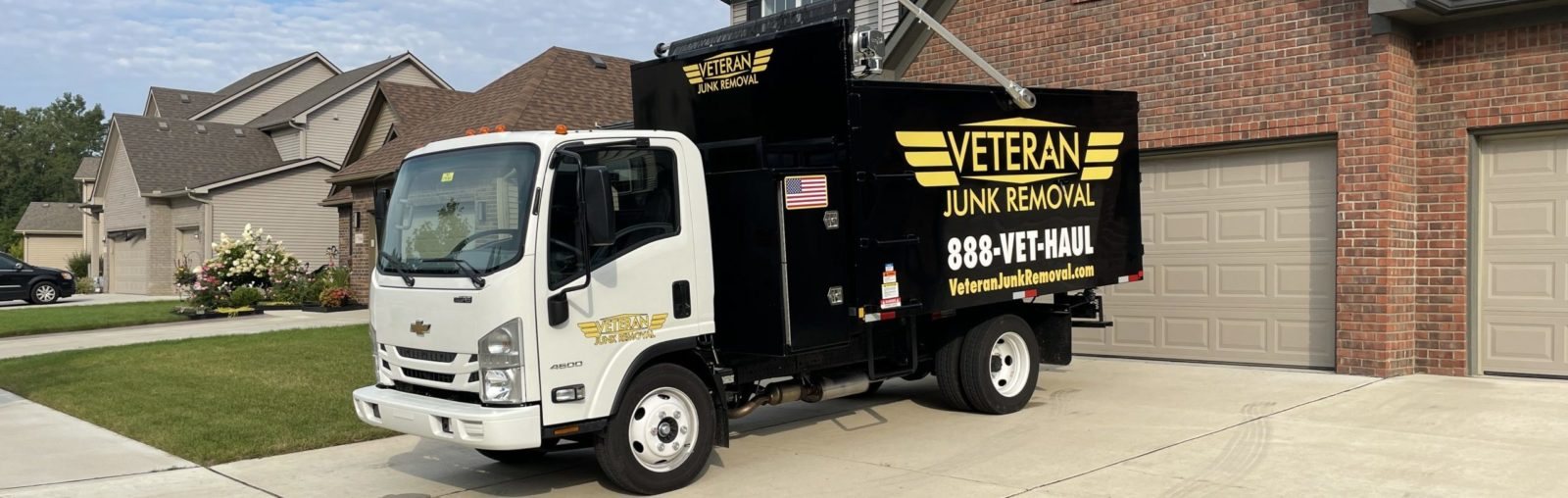 The Veteran Junk Removal truck parked in the driveway of a brick home